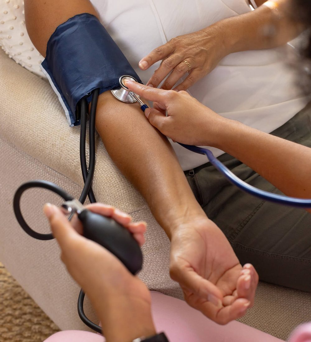 mature-biracial-woman-getting-blood-pressure-checked-by-young-biracial-woman-home (1)